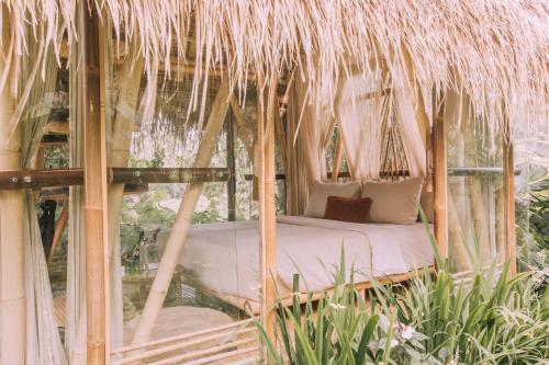 a bed in a thatched tent in a garden at Hideout Eco Bamboo House Bali in Selat