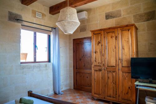 a bedroom with a large wooden cabinet and a television at Laremi Gozo B&B in Nadur