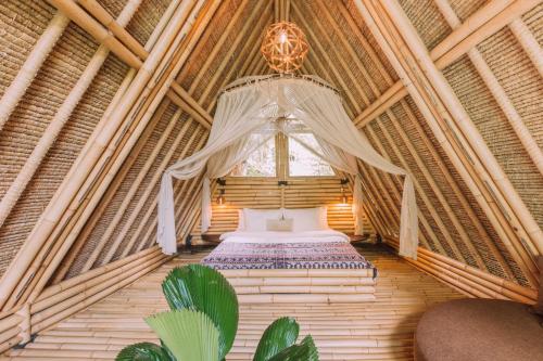 a bedroom in a bamboo house with a bed in it at Hideout Eco Bamboo House Bali in Selat