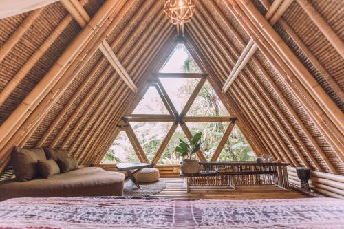a room with a bed and a large window at Hideout Eco Bamboo House Bali in Selat