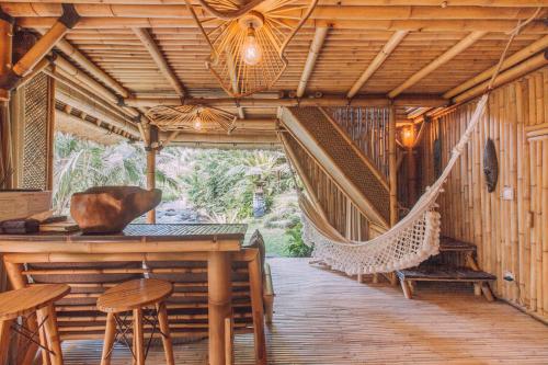 a porch with a hammock in a wooden house at Hideout Bali in Selat