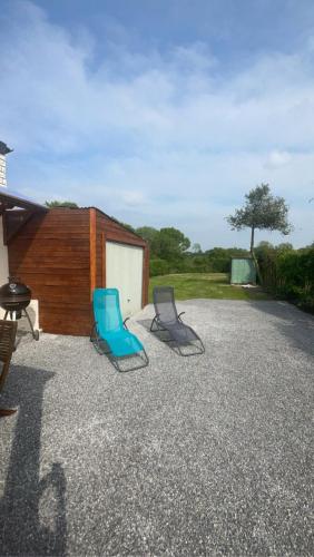 two blue chairs sitting on the gravel in front of a building at LE CHANT DES OISEAUX arrivée autonome in Sorbais
