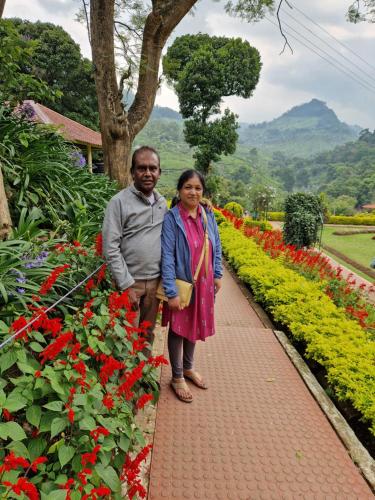 a man and woman standing next to a garden of flowers at Narmada Holiday Home in Ooty