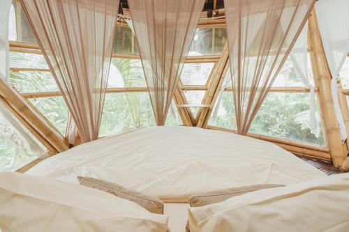 a bed in a room with a large window at Hideout Eco Bamboo House Bali in Selat
