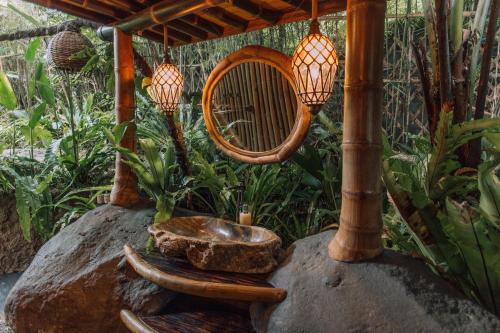 a bird bath on a rock with lights on it at Hideout Eco Bamboo House Bali in Selat