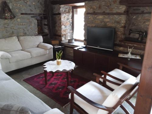 a living room with a couch and a tv at Traditional House "Elisavet" in Próti