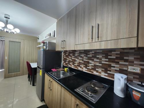 eine Küche mit einer Spüle und einem schwarzen Kühlschrank in der Unterkunft EZBeds Mall of Asia in Manila