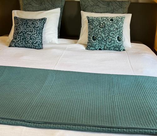 uma cama com lençóis e almofadas verdes e brancos em Côté Source " Appartement " em Francorchamps