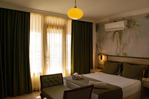 a bedroom with a bed and a chair and a window at Akkan Beach Hotel in Bodrum City