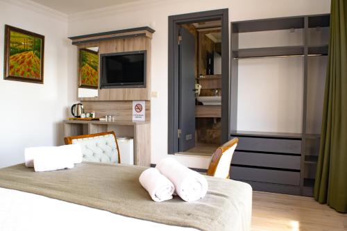 a bedroom with a bed with white pillows and a television at Akkan Beach Hotel in Bodrum City