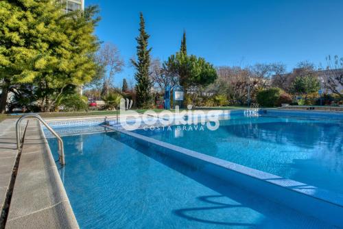 una piscina en un parque con árboles en Derbi II Apartamento muy acogedor con piscina comunitaria a pocos minutos de la playa y Port d'Aro, en Platja d'Aro