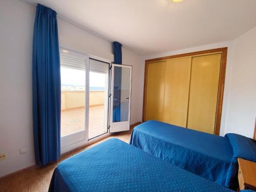 a bedroom with two beds and a window with a beach at Apartamentos Maracay in Roquetas de Mar