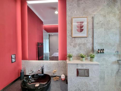 a bathroom with a black sink and red walls at Panorama Deluxe Aparthotel in Cluj-Napoca