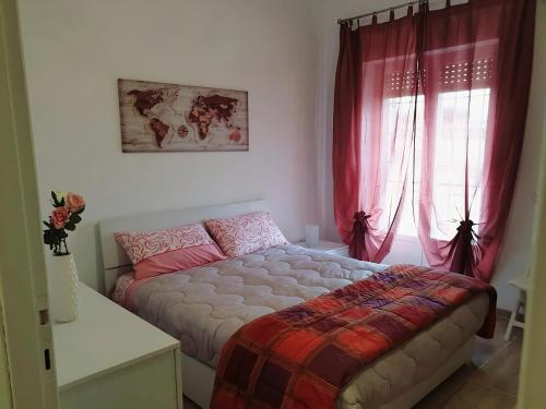 een slaapkamer met een bed en een raam met rode gordijnen bij Attico con terrazzo Relax in Ladispoli