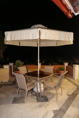 a table and chairs with an umbrella on a patio at Heaven Apartments in Agia Marina Nea Kydonias