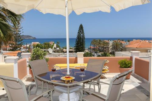 a table with chairs and an umbrella on a balcony at Heaven Apartments in Agia Marina Nea Kydonias