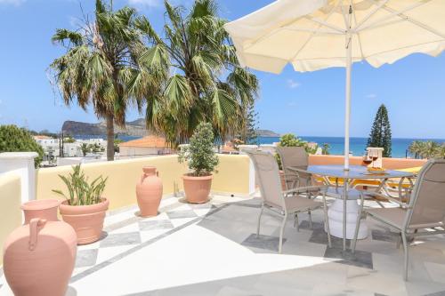 a patio with a table and chairs and an umbrella at Heaven Apartments in Agia Marina Nea Kydonias
