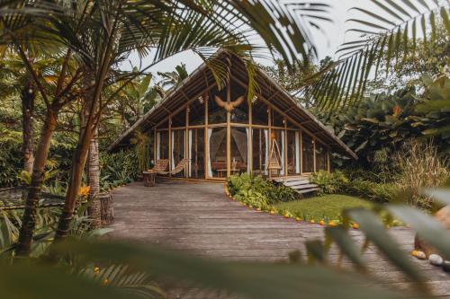 a wooden walkway leading to a building in a forest at Hideout Eco Bamboo House Bali in Selat