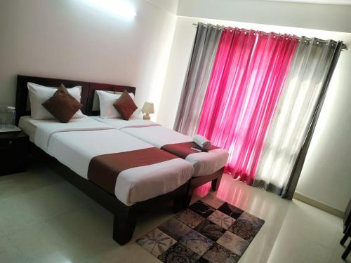 a bedroom with a large bed with a red curtain at 2 BHK Corporate Service Apartment Manyata Tech Park in Bangalore