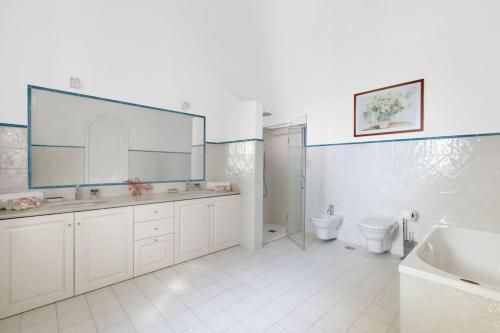 a bathroom with two sinks and a toilet and a mirror at La Villa Positano - Luxury villa with private sea access in Positano