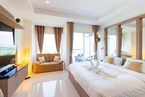 a hotel room with a large bed and a television at Nam Talay Jomtien Beach - Rooftop Ocean View - Close to Beach, Pool & Gym in Na Jomtien