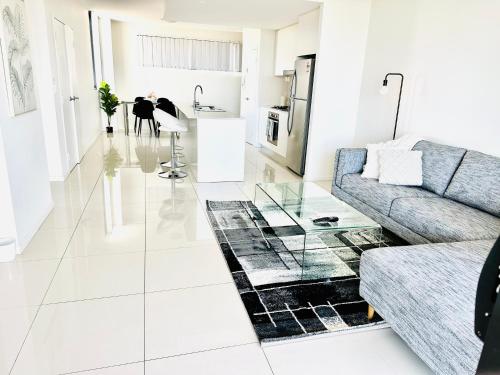 sala de estar con sofá y mesa de cristal en Modern 2 bedroom & 2 bathroom apartment with stunning Sydney CBD & Skyline Views!, en Liverpool
