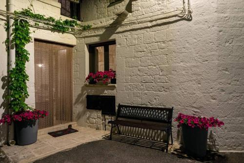 a bench sitting in front of a building with flowers at Il Trullo Moore Alberobello in Alberobello