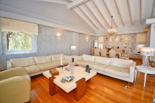 a living room with a white couch and a table at Villa Helios Corfu Kassiopi in Kelliá
