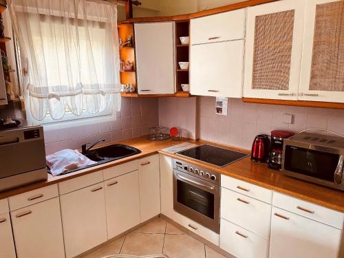 kuchnia z białymi szafkami i kuchenką w obiekcie Pavlina w mieście Kallithea