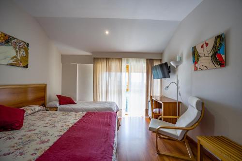 a hotel room with two beds and a chair at Los Barruecos - BGA HOTELES in Malpartida de Cáceres