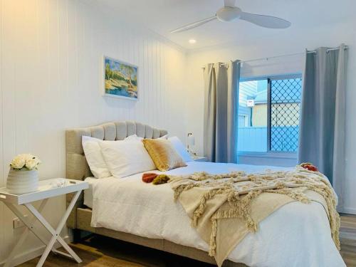 a bedroom with a bed and a table and a window at Noraville Hamptons Style Beach House in Norah Head