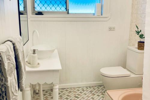 a bathroom with a sink and a toilet and a window at Noraville Hamptons Style Beach House in Norah Head