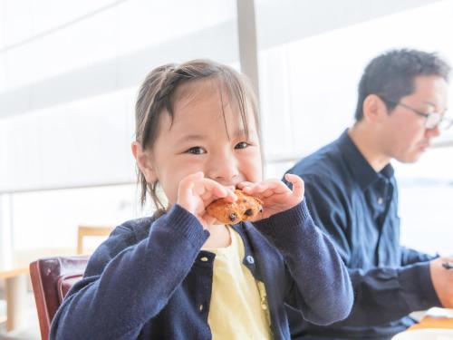 a little girl eating a piece of food with her hands at Nichinankaigan Nango Prince Hotel in Nichinan