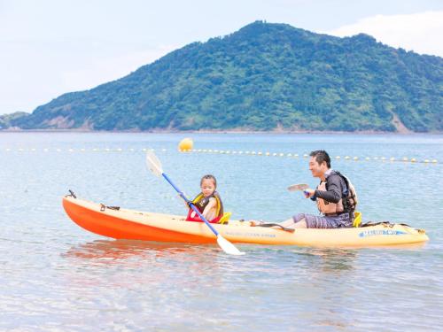 a man and a girl in a kayak in the water at Nichinankaigan Nango Prince Hotel in Nichinan