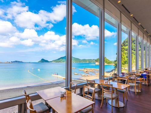 Nichinankaigan Nango Prince Hotel في نيتشينان: مطعم به طاولات وكراسي ومطل على المحيط