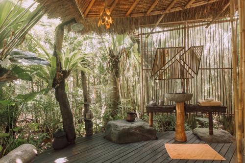 a wooden deck with a table in a forest at Hideout Eco Bamboo House Bali in Selat