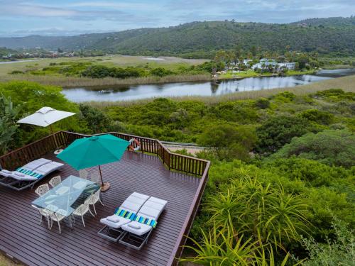 a deck with chairs and an umbrella and a river at RiverView in Wilderness