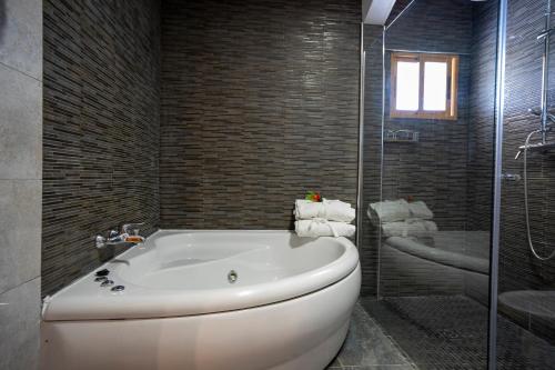 ein Badezimmer mit einer weißen Badewanne und einer Glasdusche in der Unterkunft Hotel Los Barruecos in Malpartida de Cáceres