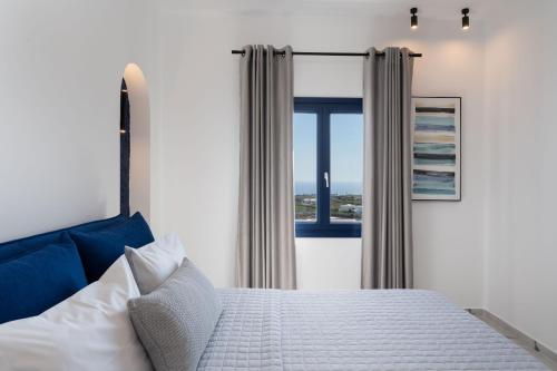 a bedroom with a bed and a large window at Amera Suites in Fira