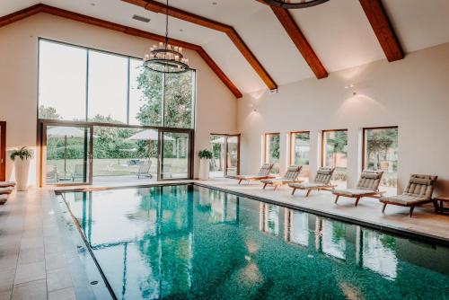 a swimming pool with chairs and windows in a house at Der Eisvogel - Wellness- & Genusshotel in Bad Gögging