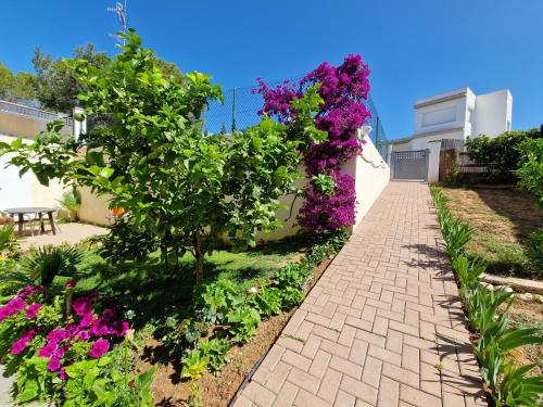 a brick walkway in a garden with purple flowers at Apartament Ca la Rosa in L'Ampolla