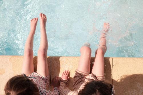two women laying on the edge of a swimming pool at INSPIRE Villages - Marennes Oléron in Marennes