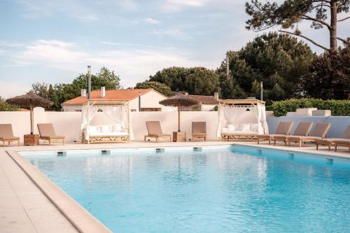 a swimming pool with chairs and umbrellas at INSPIRE Villages - Marennes Oléron in Marennes