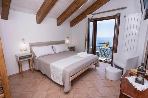 a bedroom with a bed and a balcony with the ocean at Agriturismo Punta San Lazzaro in Agerola