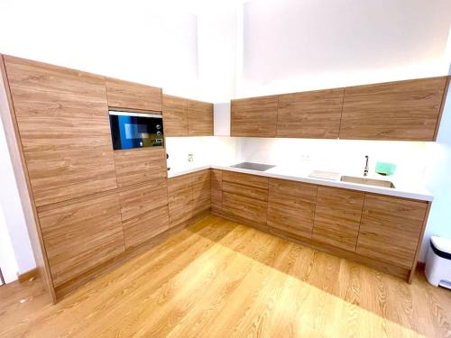 una cocina con armarios de madera y fregadero en Apartamento playa del Postiguet en Alicante