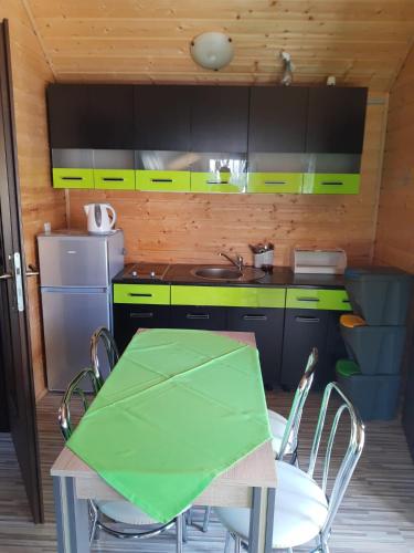 a kitchen with a table with a green table cloth on it at OLIWIA DOMKI LETNISKOWE in Bobolin