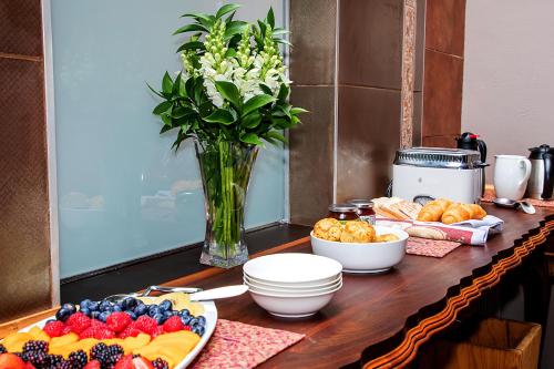 a table with a plate of fruit and a vase of flowers at aHa Guest House in Sea View