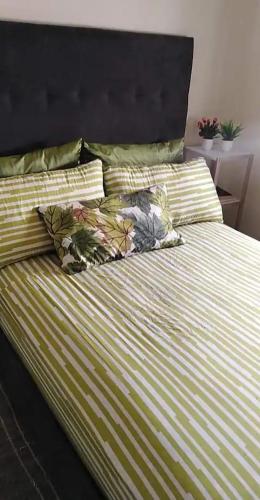 a bed with green and white striped sheets and pillows at Appartement Tamaris couple mariés in Tamaris