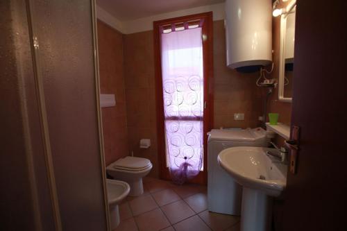 baño con aseo y lavabo y ventana en Salina, en Rosolina Mare