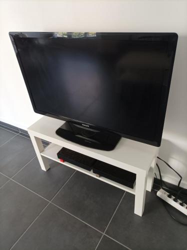 Elle comprend une télévision à écran plat sur une table blanche. dans l'établissement O'Couvent - Appartement 91 m2 - 4 chambres - A521, à Salins-les-Bains